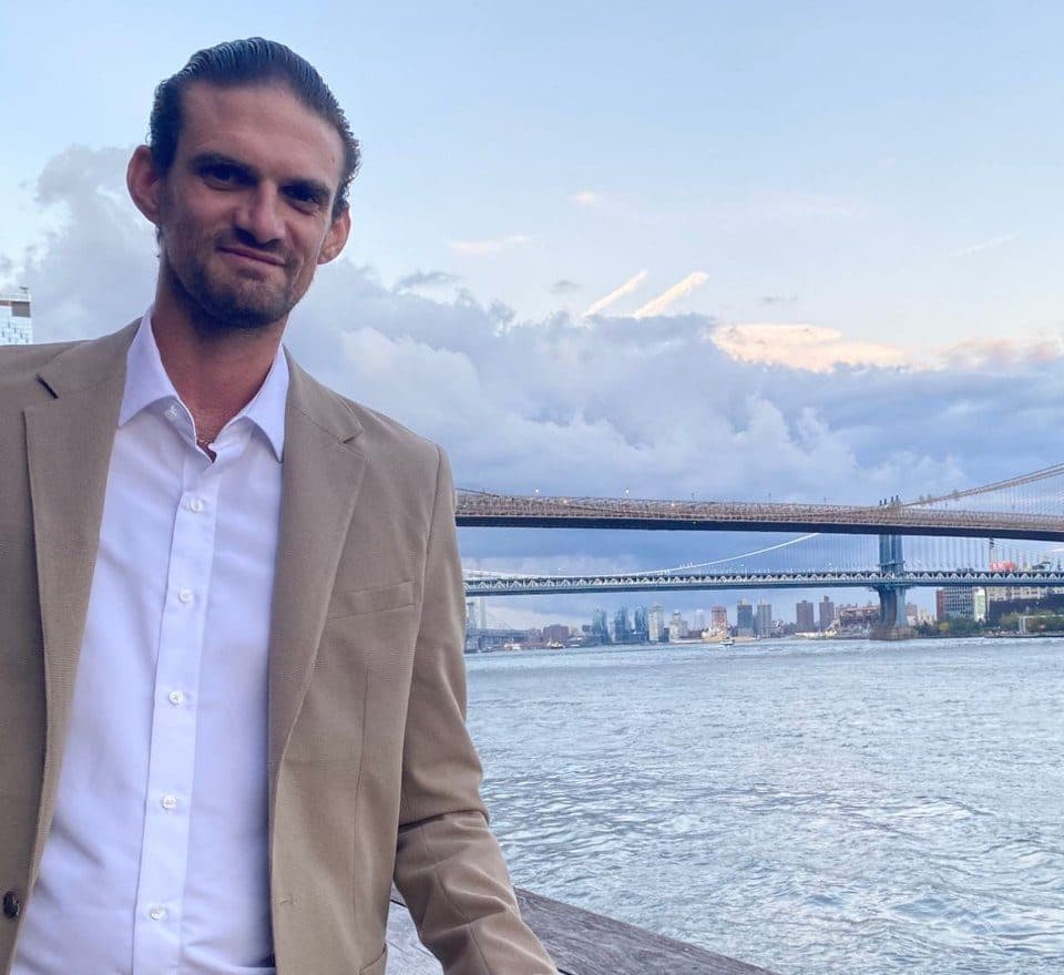 Sam Friedman on the Brooklyn waterfront with the Manhattan Bridge behind him